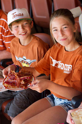 Two little kids with a plate of bacon