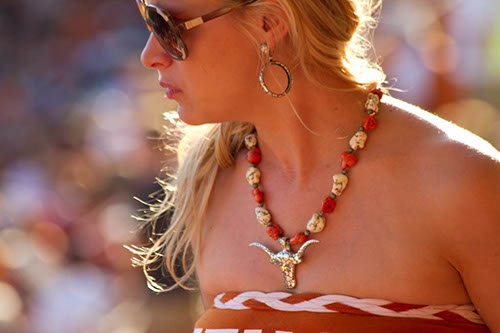 A woman in burnt orange with Longhorn jewelry